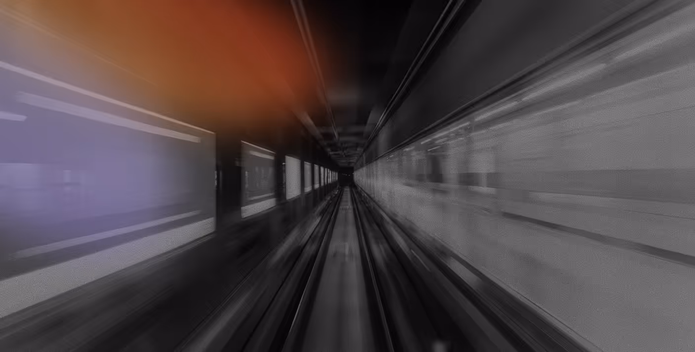 Blurred view inside a dark tunnel with lighted panels on the walls, creating a sense of speed.